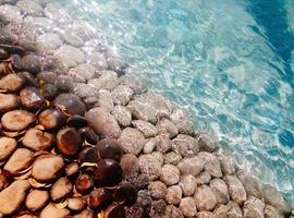große Kiesel und Steine unter blauem transparentem Wasser am Strand