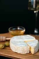 Camembert Käse, Oliven, Honig und Weinglas von Weiß Wein auf ein dunkel Hintergrund. Nahansicht. Kopieren Raum. selektiv Fokus. foto