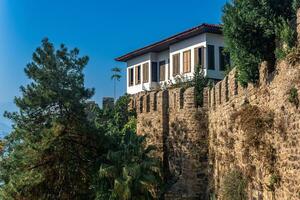 traditionell Haus mit ein gefliest Dach und Fensterläden hinter ein uralt Festung Mauer im Kaleici, das historisch Kreis von Antalya foto