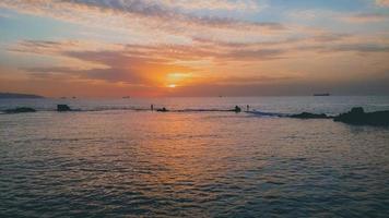 Wunderschöner Blick auf den Sonnenuntergang über dem Meer mit Schiffen und Fischersilhouette