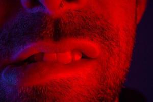 Makro Nahaufnahme eines Mannes mit verführerischem Gesichtsausdruck, der sich auf die Lippen beißt foto