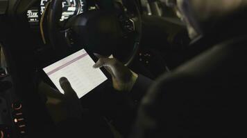 schließen oben von Hände mit Digital Tablette während Sitzung im ein Wagen. Aktie. Geschäftsmann prüft das Anteile auf das Tablette im das Auto foto