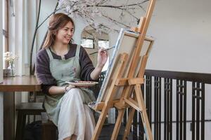 jung weiblich Künstler funktioniert auf abstrakt Acryl Gemälde auf Segeltuch im Kunst Gemälde Studio. foto