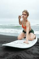 Sinnlichkeit Frau Surfer Streiks Pose auf Knie oben auf Surfbrett. Sport Mode Modell- suchen beim Kamera foto