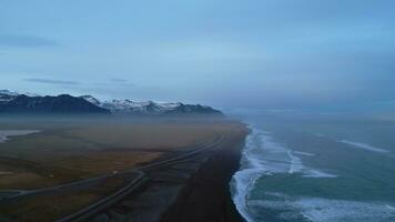 Island Landschaft schwarz Sand Strand mit atlantisch Ozean Ufer, majestätisch nordisch Land mit natürlich Landschaft. Drohne Schuss von isländisch Natur mit Wellen Schlagen das Küste, Horizont. schleppend Bewegung. foto