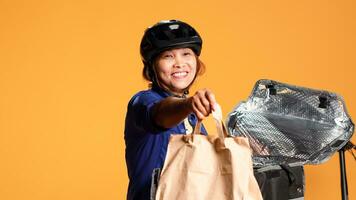 schließen oben Schuss von Kurier ankommen zu Kunde Adresse, nehmen Mahlzeit Tasche aus von thermic Rucksack. glücklich bipoc Fahrrad Fahrer liefern Mittagessen zu Klient, isoliert Über Studio Hintergrund foto