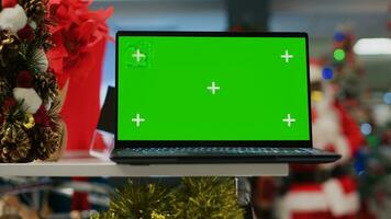 Chroma Schlüssel Laptop auf Weihnachten dekoriert Kleidung Geschäft Anzeige Tabelle zeigen Information Über Produkte. Grün Bildschirm Gerät im festlich schmücken Mode Boutique nützlich zum suchen oben Kleider Preise foto