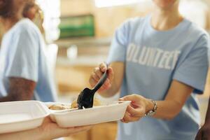 beim wohltätig Essen Antrieb, kaukasisch Dame ist gezeigt Angebot ein warm Mahlzeit zu ein benachteiligt hungrig obdachlos Person. ein Nahansicht von ein Mannschaft von humanitär Linderung Arbeitskräfte verteilen kostenlos Lebensmittel. foto