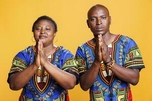 afrikanisch amerikanisch Mann und Frau Paar betteln und fragen zum Hilfe während Stehen mit Palmen gefaltet Porträt. Paar beten zu Gott und Bitten zum Segen während suchen beim Kamera foto