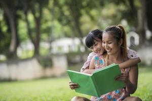 Mutter und Tochter lesen ihrer Tochter im Park ein Märchen vor foto