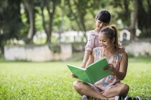 Mutter und Tochter lesen ihrer Tochter im Park ein Märchen vor foto