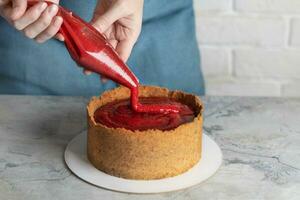 Frau weiblich Hände Herstellung Käsekuchen, dekorieren Vanille Käsekuchen mit Erdbeere Möbel im das Küche schließen oben horizontal foto