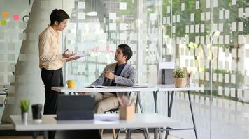 Zwei junge Geschäftsleute diskutieren über die Arbeit, um Kunden in einem modernen Büro zu präsentieren. foto