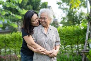 asiatische ältere frau mit pflegerin, die tochter geht und mit glücklich im naturpark umarmt. foto