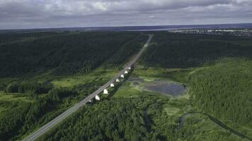 oben Aussicht von Brücke Vorbeigehen durch im Wald. Clip. Autobahn geht vorbei durch Sumpf im Wald zu Stadt auf Horizont. der Verkehr auf ländlich Autobahn im wolkig Wetter foto