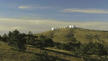 oben Aussicht von Weiß gewölbt Gebäude von Observatorien auf hügel. Schuss. astronomisch Forschung Anlagen und groß Observatorien gelegen beim oben mit schön Sonnenuntergang Himmel und Wolken foto