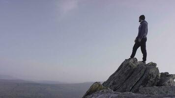 Mann auf oben von das Berg. ein jung, sportlich Mann steht auf ein hoch Felsen foto