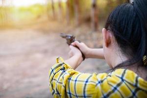 Porträt der Bauer-Asea-Frau, die ein gelbes Hemd bei der Schießerei aus einer alten Revolverpistole in der Farm trägt foto