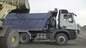 Russland, Moskau - - kann 7, 2022. Bagger Ladungen Dump LKW mit Erde beim Konstruktion Seite? ˅. Szene. Lastwagen sind Arbeiten und Clearing Konstruktion Seite? ˅. Bagger gießt Erde in Dump LKW foto