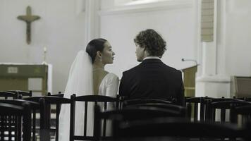Braut und Bräutigam beim das Hochzeit Zeremonie im modern Kirche. Aktion. Frau und Mann Sitzung zusammen unter leeren Sitze. foto