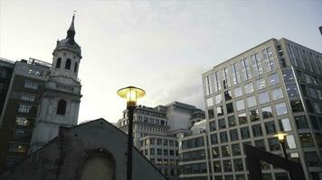 Nahansicht von Gelb Straße Beleuchtung im das Center von London in der Nähe von das modern Glas Wolkenkratzer gegen das Blau Abend Himmel. Aktion. Abend Stadt Landschaft foto