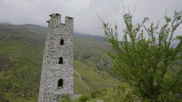 Stein Türme von uralt Gebäude im Berge. Aktion. alt Stein Turm auf Hintergrund von Grün Berge. konserviert Turm von uralt Struktur im Berge foto