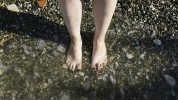 oben Aussicht von Füße beim das Strand mit Meer Wellen. Konzept. verbinden zu Natur, schön Beine und Füße von ein Frau mit ihr Nägel gemalt schwarz Sein gewaschen durch Meer oder Ozean Wellen. foto