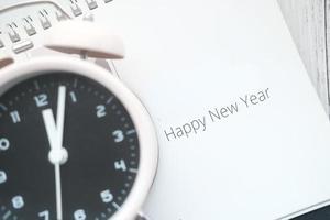 Frohes neues Jahr Text im Kalender mit Uhr auf dem Tisch