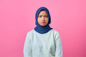 Porträt der jungen asiatischen Frau der Traurigkeit, die Kamera auf rosa Hintergrund schaut foto