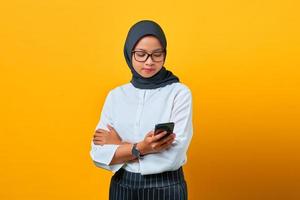 junge asiatische Frau mit Handy und SMS auf gelbem Hintergrund