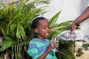 lächelnder kleiner Junge und ein Glas Wasser. foto