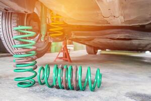 Frühling zum Schock Absorber mit Auto Instandhaltung Konzept mit Stadt Auto auf das Fußboden Zement foto