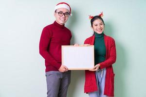 junges asiatisches paar posiert auf grünem hintergrund mit weihnachtskonzept foto