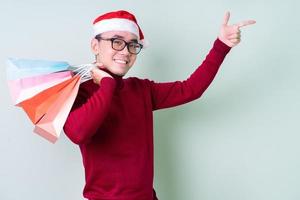 junger asiatischer Mann mit Weihnachtsmütze auf grünem Hintergrund foto