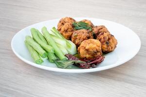 würzig gebraten Schweinefleisch oder gebraten larb im Weiß Platte von das Holz Tabelle Asien Essen ist ein würzig thailändisch Stil, Beliebt mit Bier foto