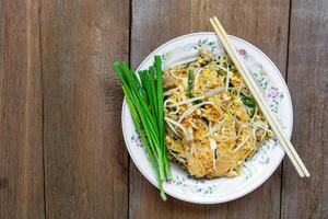 Pad thailändisch, traditionell thailändisch Gericht mit rühren gebraten Reis Nudeln, auf das Holz Tabelle Textur mit Essstäbchen und Kopieren Raum foto