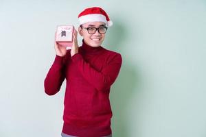 junger asiatischer Mann mit Weihnachtsmütze auf grünem Hintergrund foto