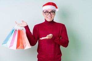 junger asiatischer Mann mit Weihnachtsmütze auf grünem Hintergrund foto