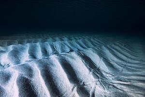 tropisch klar Blau Ozean mit Sand Unterseite auf Nacht. unter Wasser Aussicht mit künstlich Licht foto