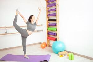 jung Frau ist tun Gymnastik im Fitnessstudio. gesund Lebensstil. lila Matte schön Pose foto