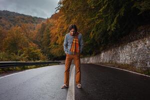 einsam Mann auf Straße, Konzept von Einsamkeit, Depression, Nachdenklichkeit. Herbst, Berge, schön Hintergrund. Abstraktion Pfad zu man selbst, Gefühl von Seele, wolkig Schlecht Wetter foto