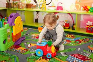 ein klein Zwei Jahre alt Mädchen Theaterstücke mit Spielzeuge im das Spielzimmer foto