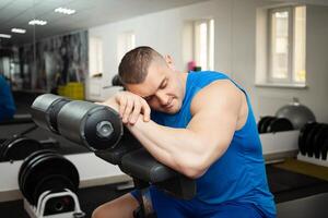 das Trainer schläft im das Arbeitsplatz im Fitnessstudio, müde nach Ausbildung, ruht. foto