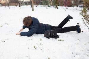 ein Mann Stürze im das Schnee. das Mann rutschte aus und war verletzt. fallen auf Eis. Winter. Fraktur, Prellung, Luxation. foto