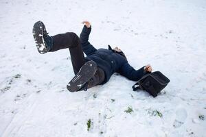 ein Mann Stürze im das Schnee. das Mann rutschte aus und war verletzt. fallen auf Eis. Winter. Fraktur, Prellung, Luxation. foto