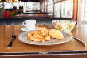 Frühstück, Abendessen, Mittagessen im ein Restaurant, Cafe. gebacken Kartoffeln mit Fleischklößchen, Caesar Salat, Kaffee Amerikaner. intervier, köstlich Essen, groß Fenster, natürlich Sonnenlicht. verschwommen Hintergrund foto