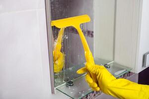 Maid mit Gummi Handschuh Reinigung Zapfhahn und Waschbecken. foto