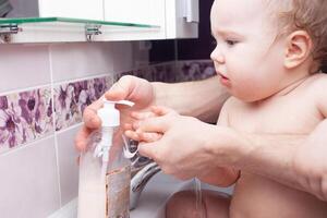 Kind wäscht Hände im Waschbecken. Jet von Wasser von klopfen. Desinfektion von Hände mit Wasser. foto