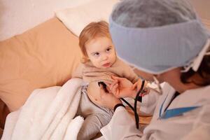 das Arzt hört zu zu das Herz und Lunge von ein wenig Mädchen. krank Baby, Zuhause Quarantäne, Coronavirus, Covid. foto