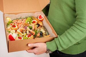 ein Box von Essen, Käse, Brot, Fisch, Garnele. Essen Lieferung zum das Unternehmen, romantisch, Büro Abendessen beim heim. schön Komposition von Essen im ein Kasten, praktisch Tragen, frisch Produkte. foto